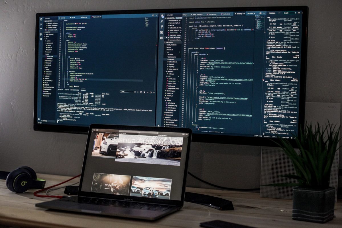 A laptop and two screens coding